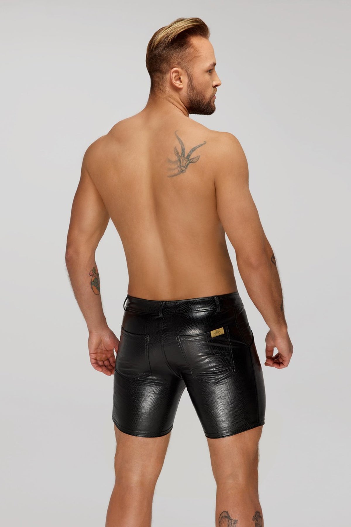Men’s black mid-length snake-pattern wetlook shorts with back pockets, rear view.
