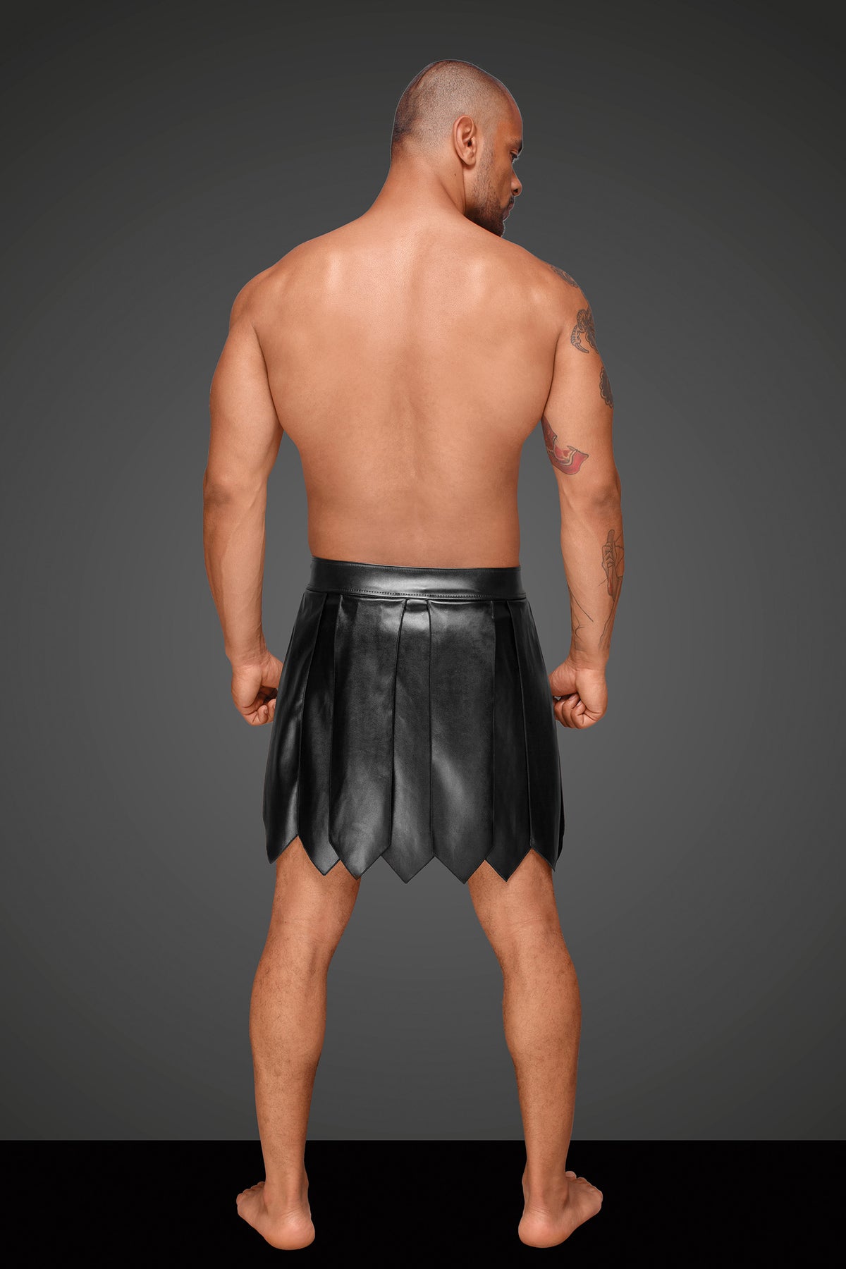 Men’s black eco-leather gladiator skirt with pointed pleats, rear view.